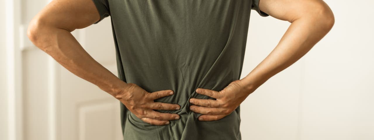 A man holding his hands against his lower back